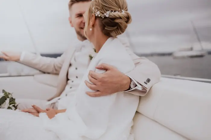 Hochzeitsfotograf Bayern Brautpaar auf einem Boot mit grauem Himmel im Hintergrund Dokumentarische Editorial Hochzeitsfotografie