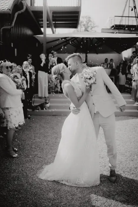 Hochzeitsfotograf Bayern Brautpaar teilt romantischen Kuss bei Hochzeit im Freien Dokumentarische Editorial Hochzeitsfotografie