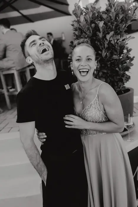 Hochzeitsfotograf Bayern Lachendes Paar in Abendkleidung auf einer Party Dokumentarische Editorial Hochzeitsfotografie
