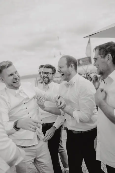 Hochzeitsfotograf Bayern Gruppe von Männern in festlicher Kleidung lacht bei einer Veranstaltung Dokumentarische Editorial Hochzeitsfotografie