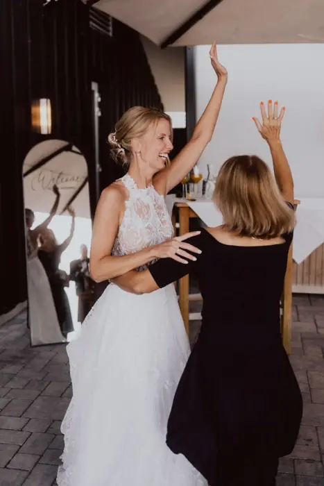 Hochzeitsfotograf Bayern Freudige Braut tanzt mit Gast auf Hochzeit Dokumentarische Editorial Hochzeitsfotografie