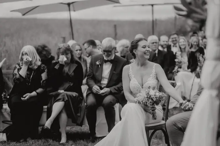 Hochzeitsfotograf Bayern Braut und Gäste bei einer Outdoor-Hochzeitszeremonie Dokumentarische Editorial Hochzeitsfotografie