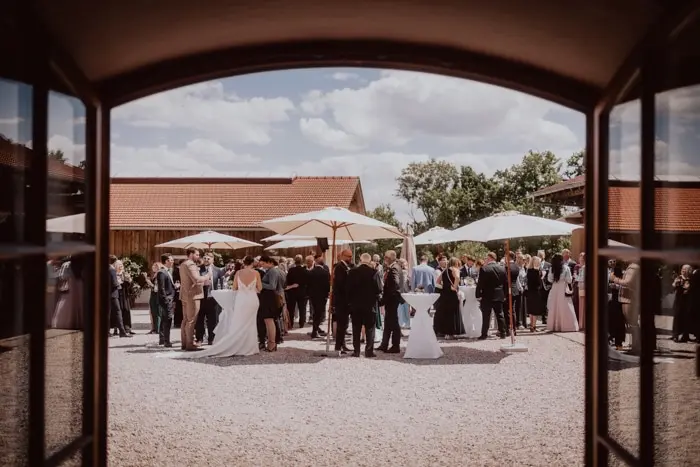 Hochzeitsfotograf Bayern Freiluft-Hochzeitsfeier in ländlicher Umgebung mit Gästen und Sonnenschirmen Dokumentarische Editorial Hochzeitsfotografie