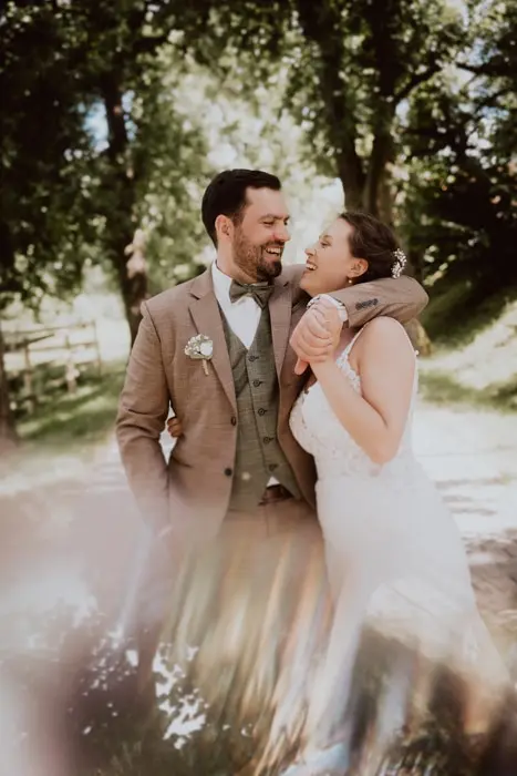 Hochzeitsfotograf Bayern Glückliches Hochzeitspaar im Freien, lächelnd und umarmend Dokumentarische Editorial Hochzeitsfotografie