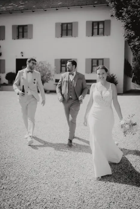 Hochzeitsfotograf Bayern Hochzeitspaar und Freund spazieren vor einem weißen Gebäude Dokumentarische Editorial Hochzeitsfotografie