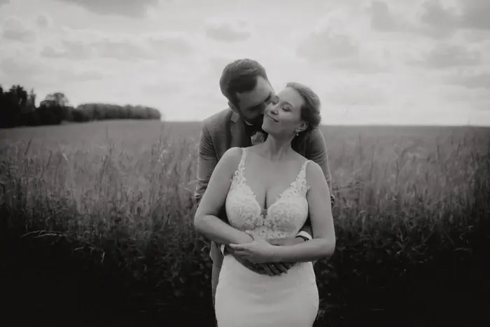 Hochzeitsfotograf Bayern Romantisches Schwarz-Weiß-Bild eines Hochzeitspaares auf einem Feld Dokumentarische Editorial Hochzeitsfotografie