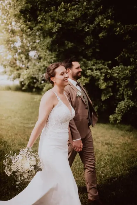 Hochzeitsfotograf Bayern Brautpaar in eleganter Kleidung, spaziert Hand in Hand im Garten Dokumentarische Editorial Hochzeitsfotografie