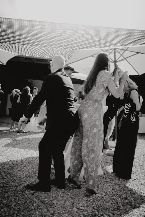 Hochzeitsfotograf Bayern Schwarzweißfoto von Menschen, die unter einem Sonnenschirm bei einer Veranstaltung tanzen Dokumentarische Editorial Hochzeitsfotografie