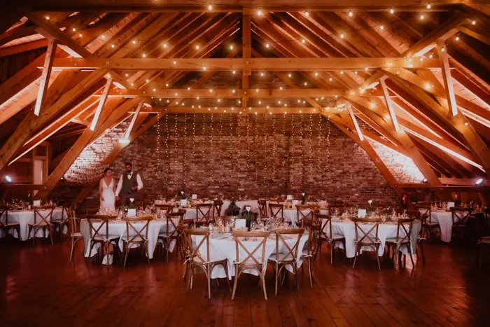 Hochzeitsfotograf Bayern Rustikales Hochzeitslokal mit Holzbalkendecke und stimmungsvoller Lichterdekoration Dokumentarische Editorial Hochzeitsfotografie