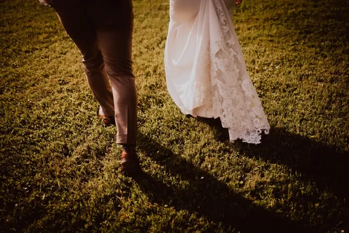 Hochzeitsfotograf Bayern Brautpaar geht über eine Wiese bei Sonnenuntergang Dokumentarische Editorial Hochzeitsfotografie