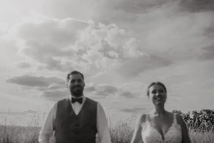 Hochzeitsfotograf Bayern Schwarz-Weiß-Foto eines Brautpaares im Freien unter wolkigem Himmel Dokumentarische Editorial Hochzeitsfotografie