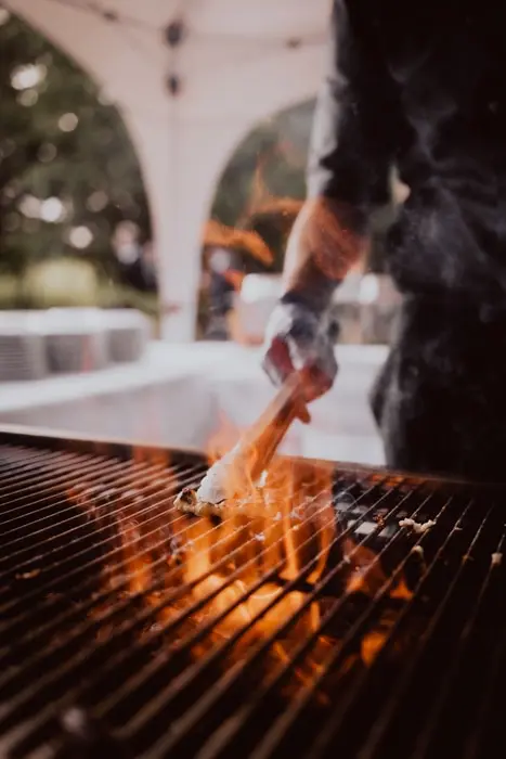 Hochzeitsfotograf Bayern Koch grillt Essen über offener Flamme bei einer Veranstaltung Dokumentarische Editorial Hochzeitsfotografie