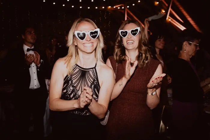 Hochzeitsfotograf Bayern Zwei Personen mit Herz-Sonnenbrillen bei einer Party Dokumentarische Editorial Hochzeitsfotografie