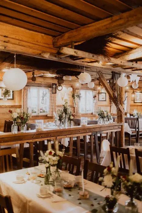 Hochzeitsfotograf Bayern Rustikales Restaurant mit Holzbalken und gedeckten Tischen Dokumentarische Editorial Hochzeitsfotografie
