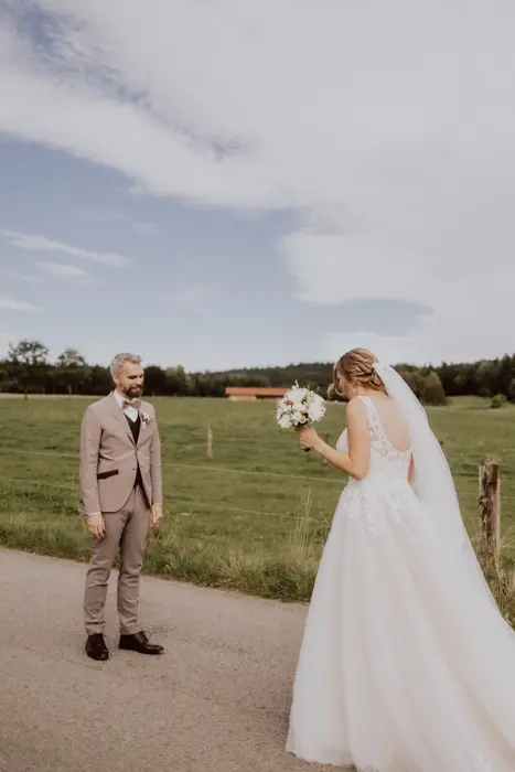 Hochzeitsfotograf Bayern Hochzeitspaar bei der ersten Begegnung auf einer Landstraße Dokumentarische Editorial Hochzeitsfotografie
