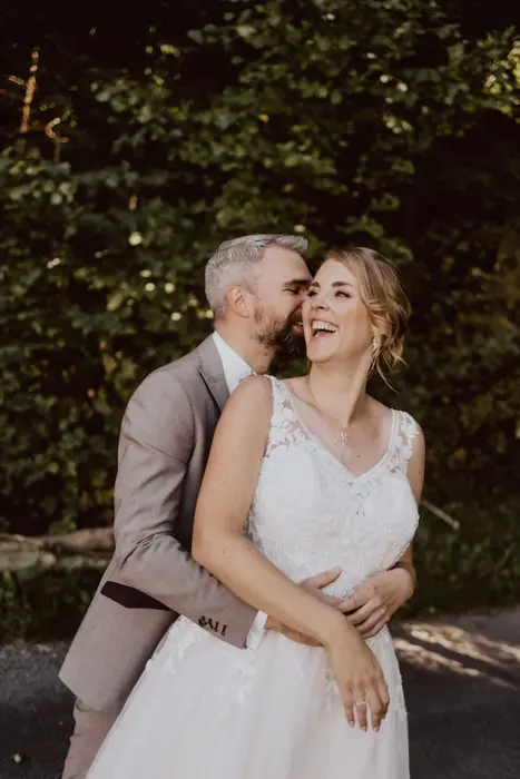 Hochzeitsfotograf Bayern Fröhliches Hochzeitspaar, das lachend im Freien posiert Dokumentarische Editorial Hochzeitsfotografie