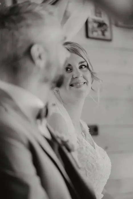 Hochzeitsfotograf Bayern Schwarzweißfoto eines lächelnden Brautpaars in rustikaler Umgebung Dokumentarische Editorial Hochzeitsfotografie