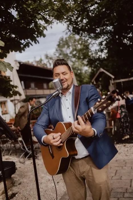 Hochzeitsfotograf Bayern Mann spielt Gitarre und singt auf einer Outdoor-Veranstaltung Dokumentarische Editorial Hochzeitsfotografie