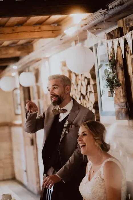 Hochzeitsfotograf Bayern Brautpaar lacht während der Hochzeitsfeier in rustikaler Scheune Dokumentarische Editorial Hochzeitsfotografie