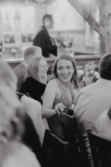 Hochzeitsfotograf Bayern Lächelnde Frau bei einer geselligen Feier in einem Restaurant Dokumentarische Editorial Hochzeitsfotografie