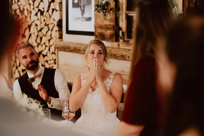 Hochzeitsfotograf Bayern Braut hört Hochzeitsrede in rustikalem Veranstaltungsort Dokumentarische Editorial Hochzeitsfotografie