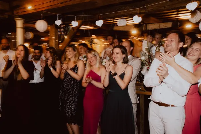 Hochzeitsfotograf Bayern Gruppe von Menschen bei einer Feier in eleganter Kleidung Dokumentarische Editorial Hochzeitsfotografie