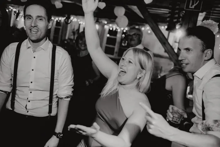Hochzeitsfotograf Bayern Menschen tanzen und feiern bei einer Party mit Lichtern im Hintergrund Dokumentarische Editorial Hochzeitsfotografie