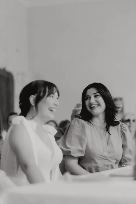 Hochzeitsfotograf Bayern Zwei lächelnde Frauen bei einer Veranstaltung in Schwarzweiß Dokumentarische Editorial Hochzeitsfotografie