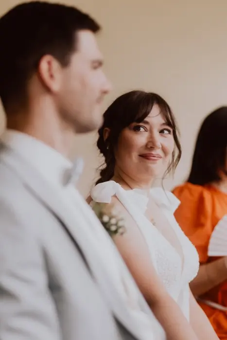 Hochzeitsfotograf Bayern Braut lächelt Bräutigam während der Hochzeitszeremonie an Dokumentarische Editorial Hochzeitsfotografie