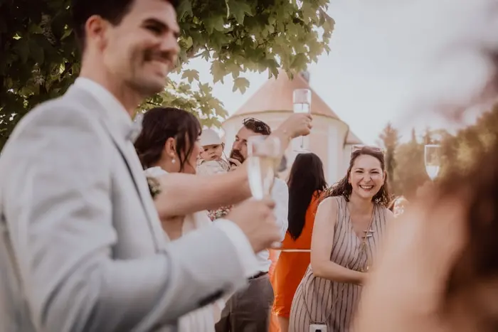 Hochzeitsfotograf Bayern Fröhliche Hochzeitsgesellschaft stößt bei Feier im Freien an Dokumentarische Editorial Hochzeitsfotografie