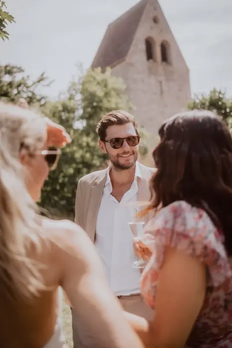 Hochzeitsfotograf Bayern Vier Personen bei einem Gartenfest vor einer Kirche Dokumentarische Editorial Hochzeitsfotografie