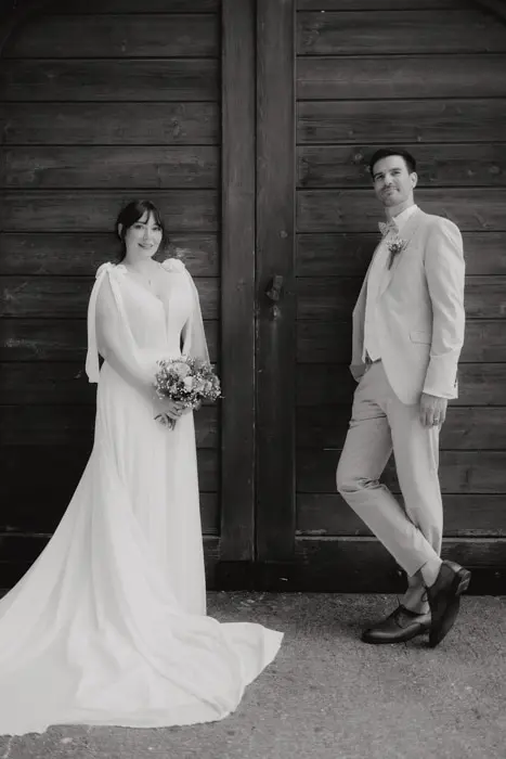 Hochzeitsfotograf Bayern Hochzeitspaar vor Holztor in Schwarz-Weiß Dokumentarische Editorial Hochzeitsfotografie