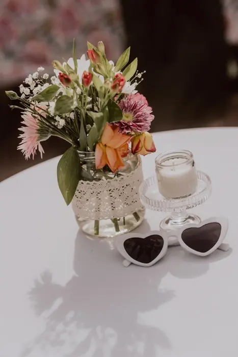 Hochzeitsfotograf Bayern Blumenstrauß in Vase mit Kerze und Sonnenbrille auf Tisch Dokumentarische Editorial Hochzeitsfotografie