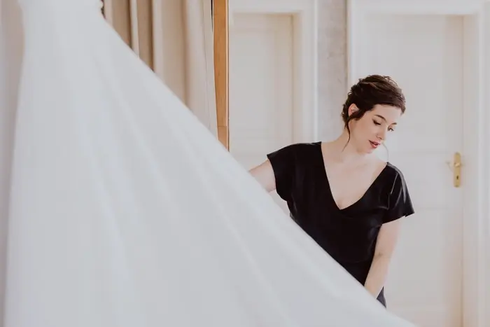 Hochzeitsfotograf Bayern Frau in schwarzem Kleid hilft beim Anpassen eines Brautkleides Dokumentarische Editorial Hochzeitsfotografie