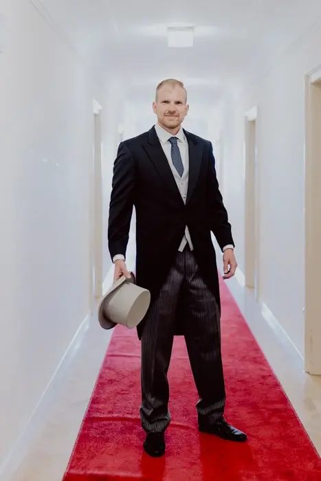 Hochzeitsfotograf Bayern Mann im Anzug im Flur mit rotem Teppich Dokumentarische Editorial Hochzeitsfotografie