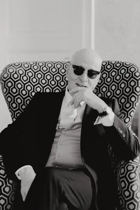 Hochzeitsfotograf Bayern Älterer Mann mit Sonnenbrille sitzt stilvoll auf einem Sessel Dokumentarische Editorial Hochzeitsfotografie