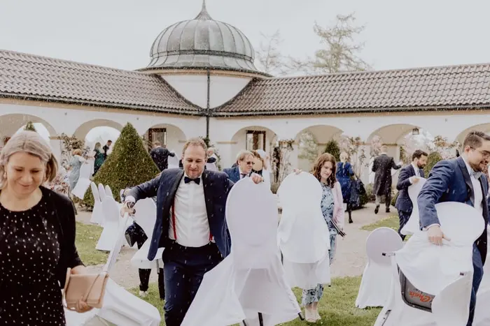 Hochzeitsfotograf Bayern Personen bei der Vorbereitung einer Veranstaltung in einer eleganten Gartenanlage Dokumentarische Editorial Hochzeitsfotografie