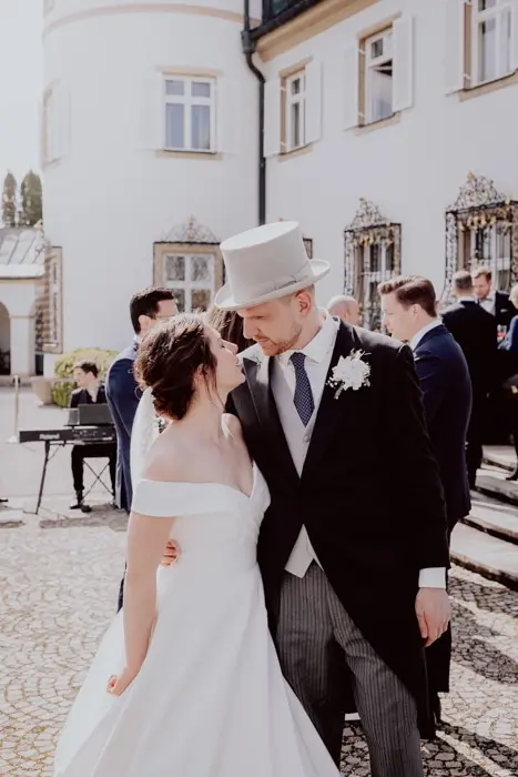 Hochzeitsfotograf Bayern Brautpaar in traditioneller Hochzeitskleidung vor einem historischen Gebäude Dokumentarische Editorial Hochzeitsfotografie
