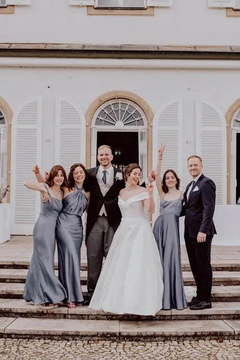 Hochzeitsfotograf Bayern Brautpaar mit Freunden vor einem historischen Gebäude auf Treppen posierend Dokumentarische Editorial Hochzeitsfotografie