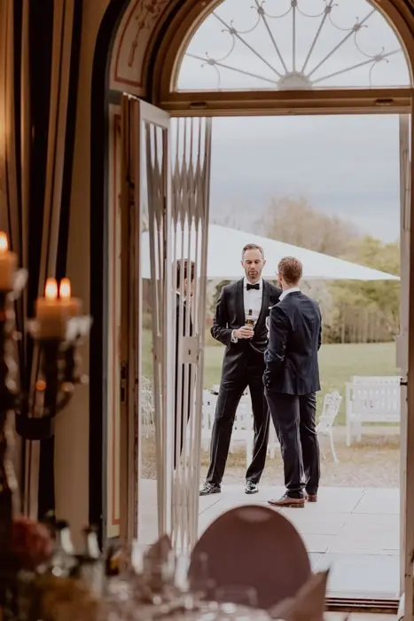 Hochzeitsfotograf Bayern Zwei Männer in Anzügen stehen draußen bei einer Veranstaltung Dokumentarische Editorial Hochzeitsfotografie