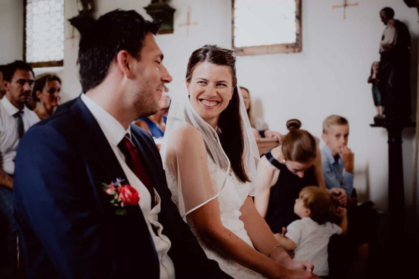 Braut lacht ihren Mann an während der Trauung in der Kirche