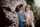 Brautpaar lehnt beim Fotoshooting an einer Steinwand und lachen