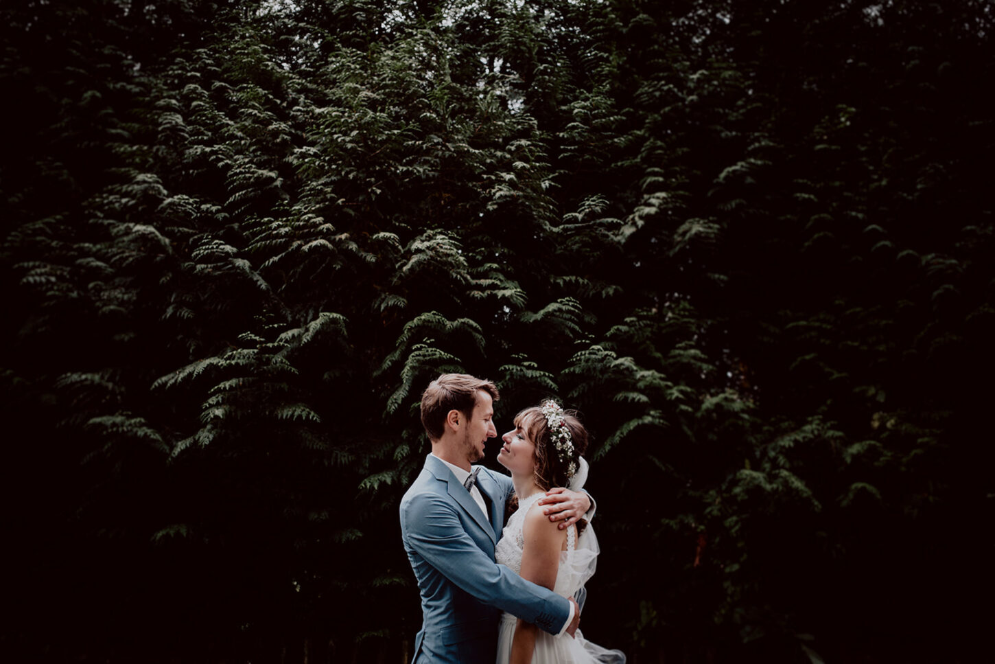 Brautpaar umarmt sich vor einer großen Hecke beim Portraitshooting im Fünfseenland