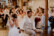 Braut und Bräutigam sitzen bei ihrer Hochzeitsfeier auf Stühlen und lachen in der Mühle in Holzham