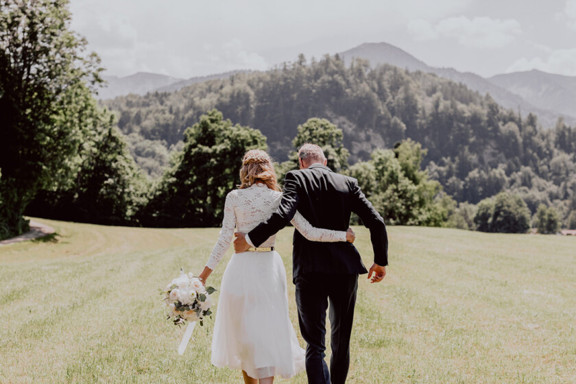 Brautpaar geht über eine Wiese auf der Hochzeit auf Gut Kaltenbrunn Tegernsee