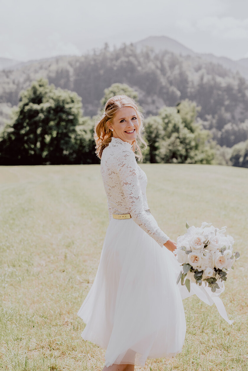Braut schaut in Kamera vor Bergkulisse auf der Hochzeit auf Gut Kaltenbrunn Tegernsee