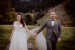 Brautpaar geht in alpiner Umgebung, hält sich die Hände und schaut in die Kamera vom Hochzeitsfotografen