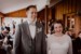 Brautpaar lacht stark bei der Trauung im Almbad Huberspitz. Im Hintergrund lachen Hochzeitsgäste.