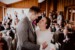 Brautpaar umarmt sich bei der Trauung im Almbad Huberspitz und lacht sich an. Im Hintergrund klatschen Hochzeitsgäste.