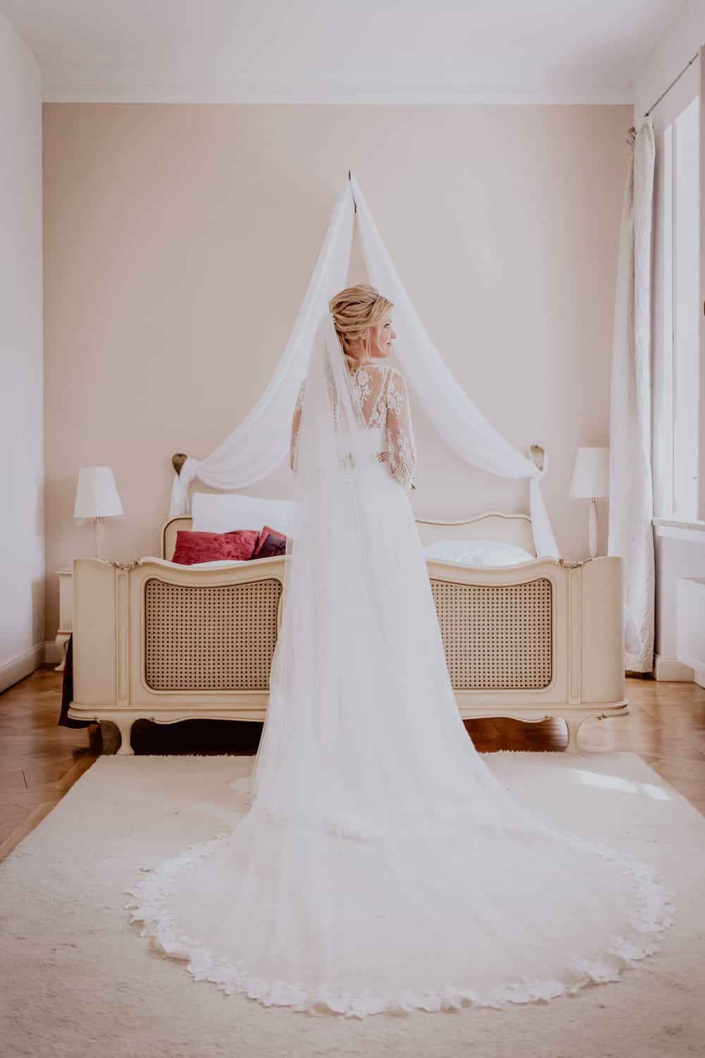 Braut im Brautkleid schaut aus dem Fenster im Schloss Blumenthal